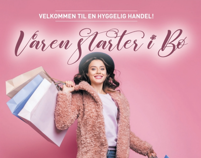 Kvinne med shoppingposer smiler foran rosa bakgrunn, med teksten Våren starter i Bø. Velkommen til hyggelig handel!