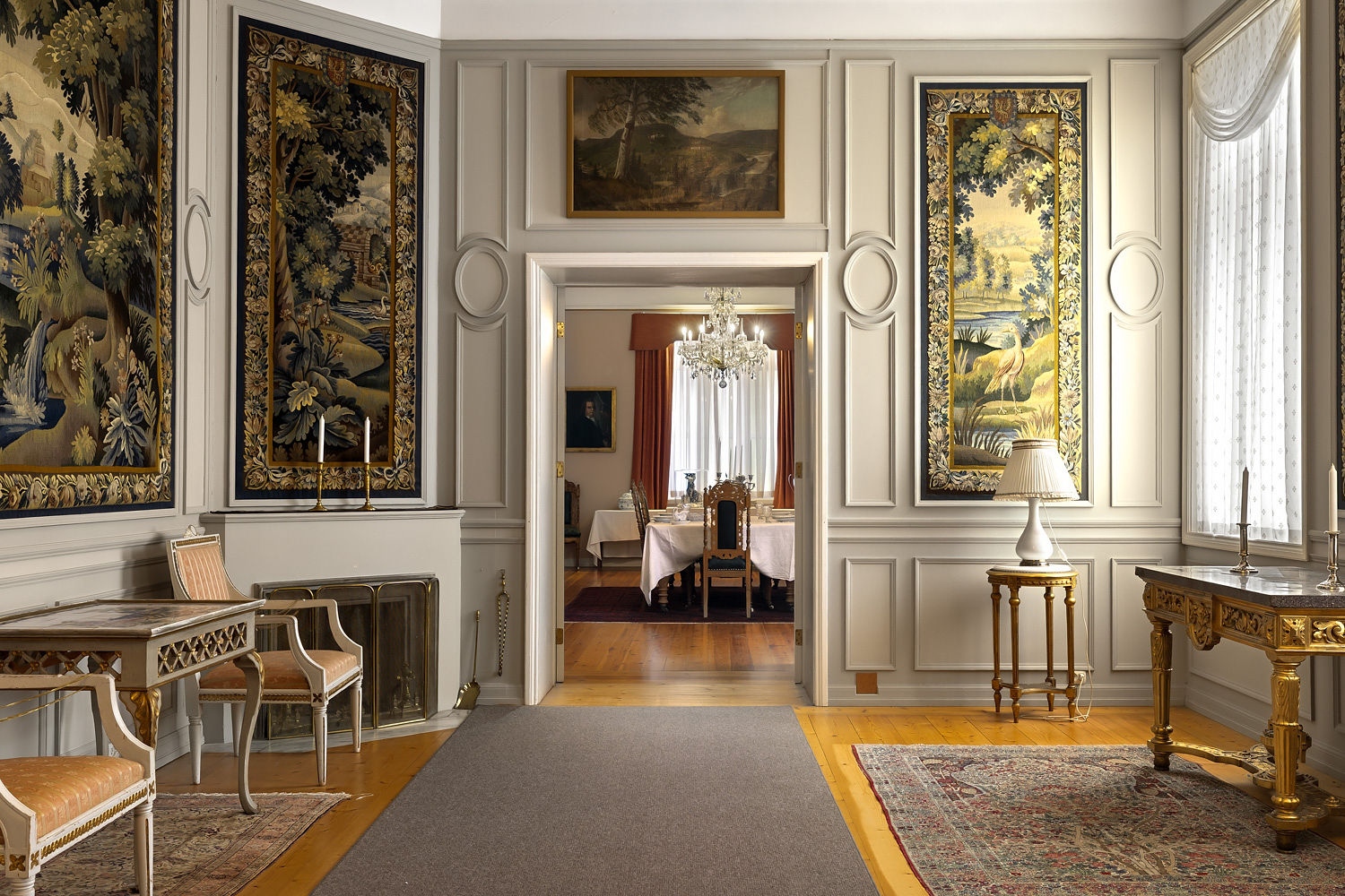 Elegant interiør med malerier og tapeter, som viser en stilig stue med spisestue i bakgrunnen.