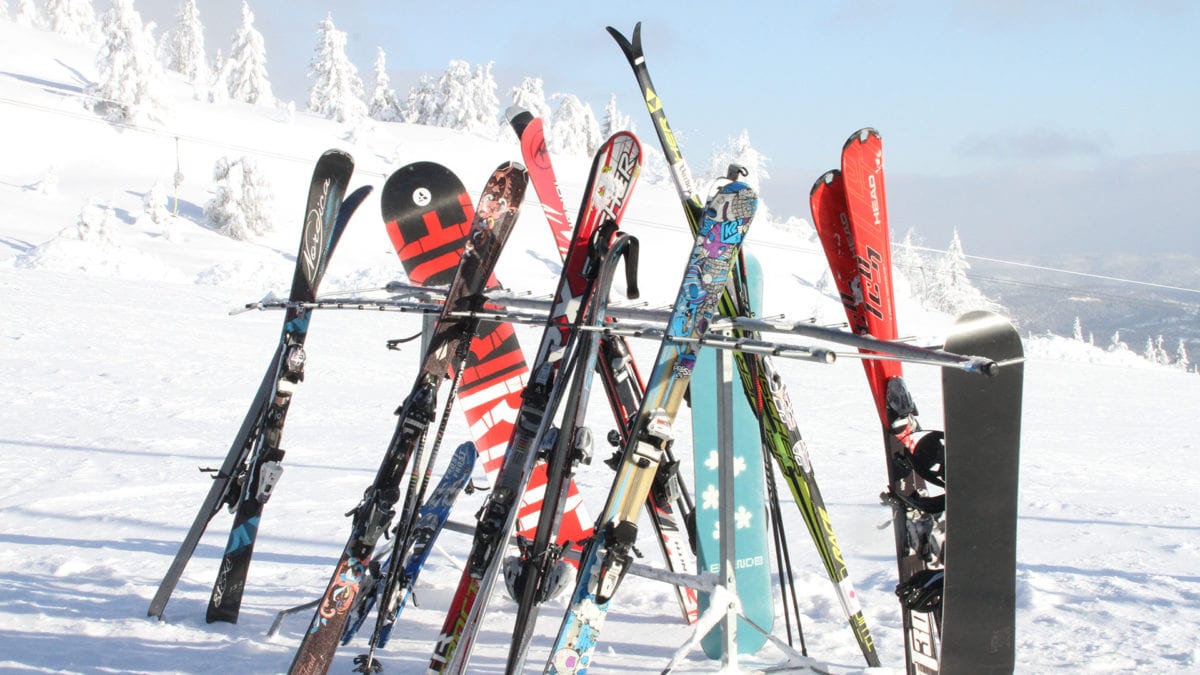 Slalåm ski som står i et stativ med snødekt natur i bakgrunnen