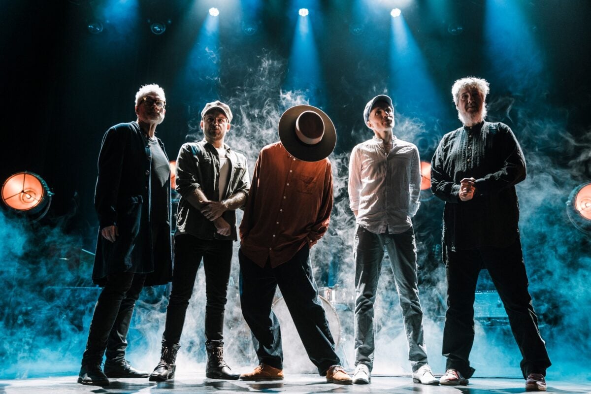 Fem musikere står på en røykfylt scene med dramatisk belysning.