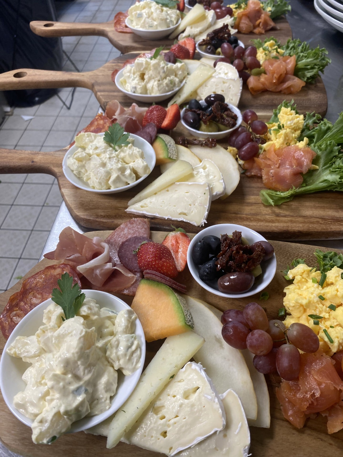 Brett med assortert brød, oster, spekemat, frukt og salat, perfekt for en smakfull lunsj eller frokost.