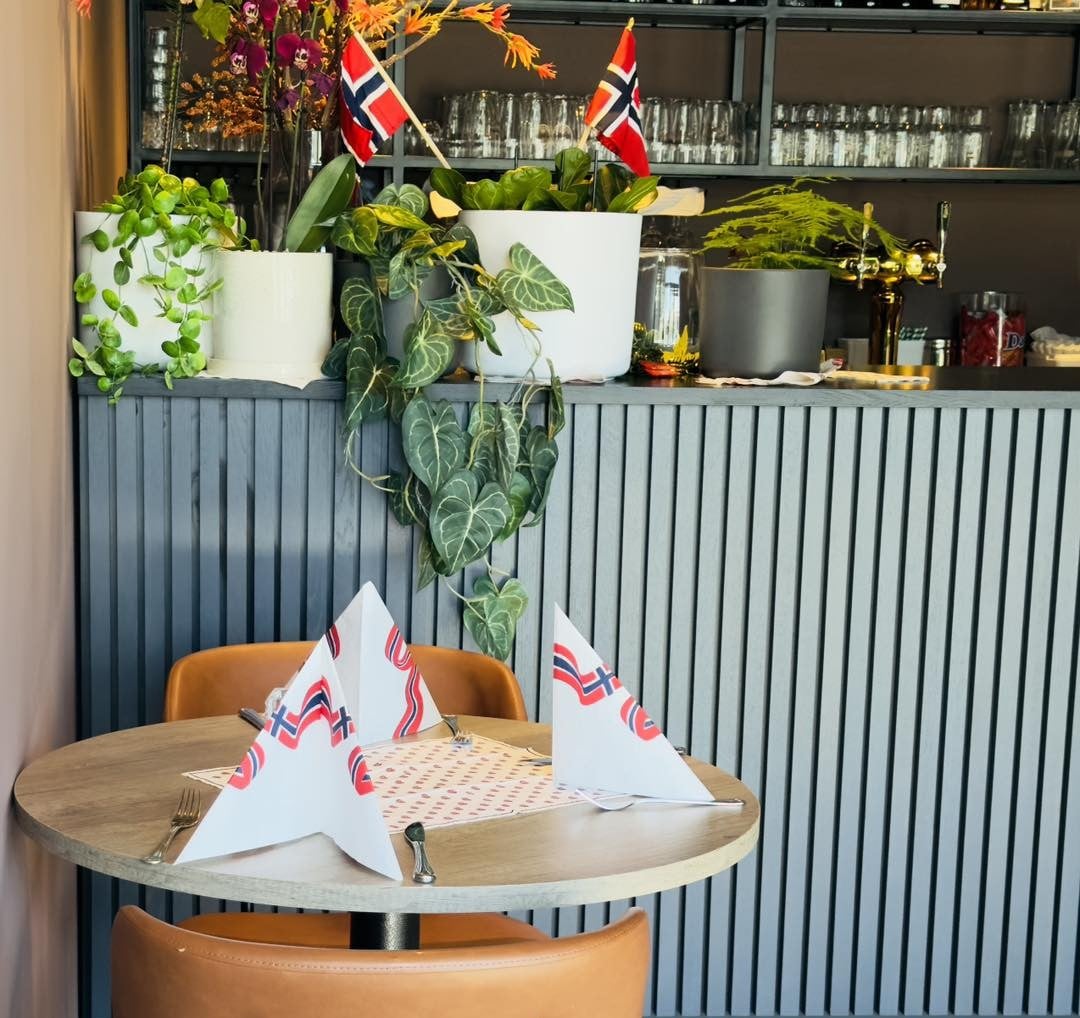 Borddekorasjon med norske flagg og planter i en koselig restaurant. Klassisk interiør og god atmosfære.